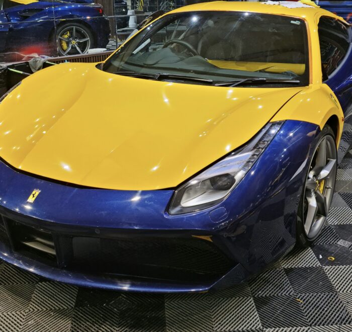 Ferrari sports car undergoing a custom colour change vinyl wrap installation in blue and yellow