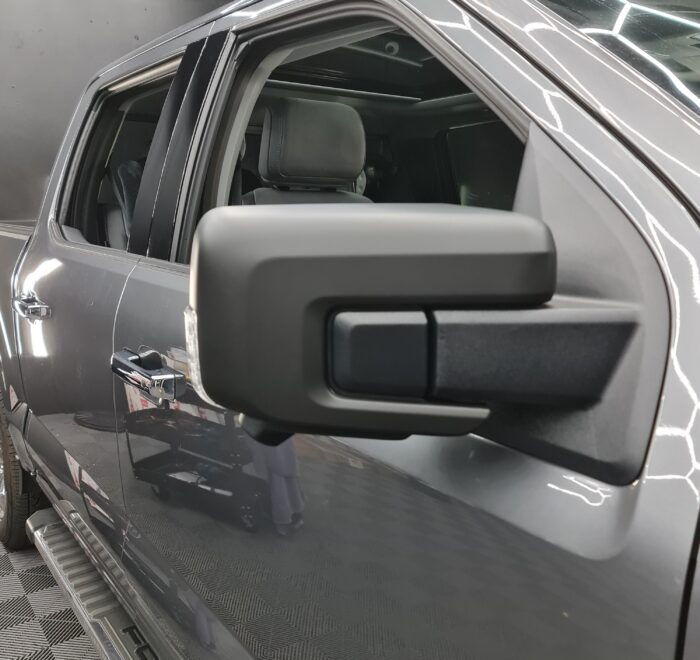 Black side mirror blackout wrap installed on a grey pickup truck as part of a vehicle styling enhancement