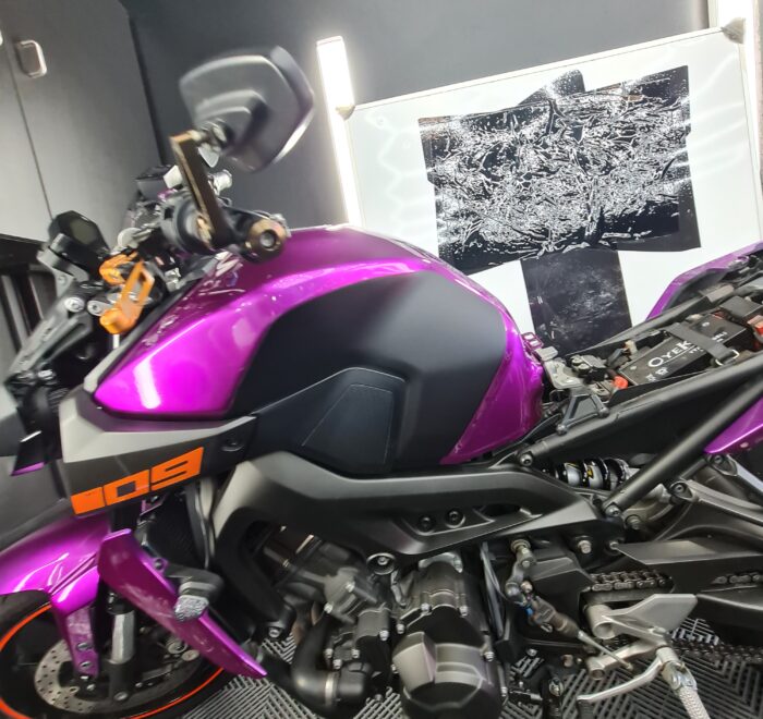 Motorcycle featuring a custom gloss purple and satin black vinyl wrap with orange accent details